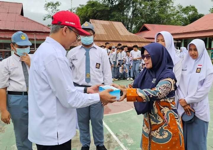 Ketua PMI Padang Panjang, Herki Toni saat serahkan masker pada Kepsek SMA  3, Kamis (7/3/2024) siang.